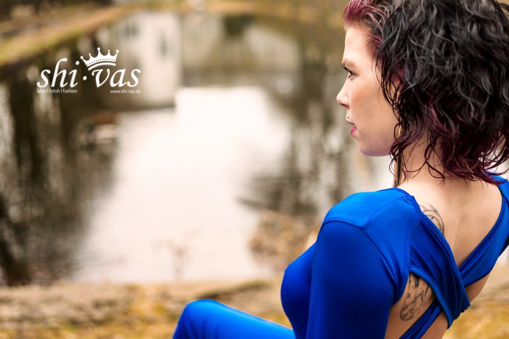 Nahaufnahme von Cocos Profil auf einer Holzbrücke; ihre nassen Locken fallen über die Schulter, der Fokus liegt auf ihrem Gesicht und dem Rückenausschnitt.