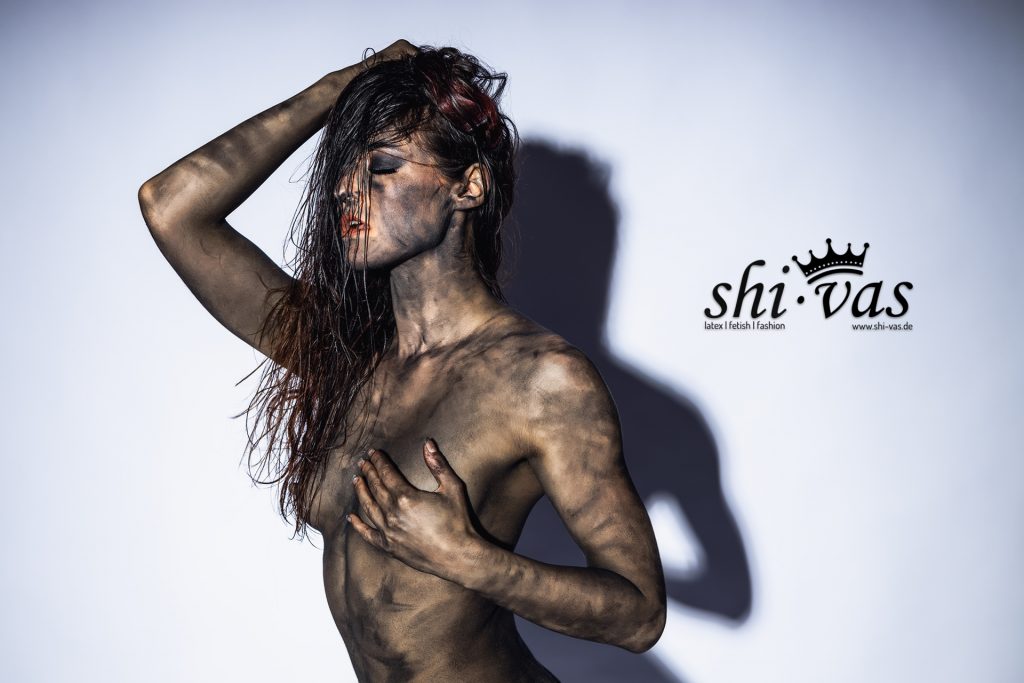 Nahaufnahme von Linas Oberkörper, eine Hand bedeckt schützend eine Brust.