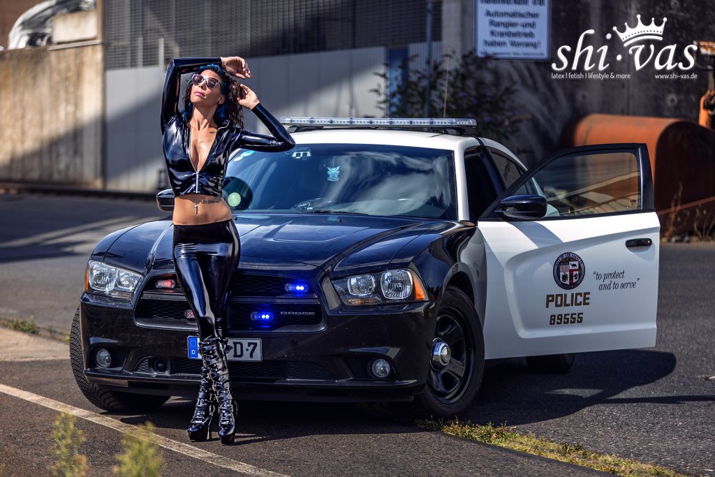 girl in latex police uniform at a policecar