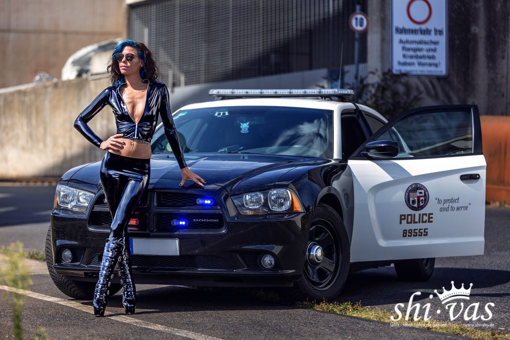 girl in latex police uniform at a policecar