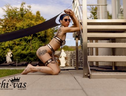 Coco kniet und lehnt mit verschränkten Armen auf der Treppenstufe.