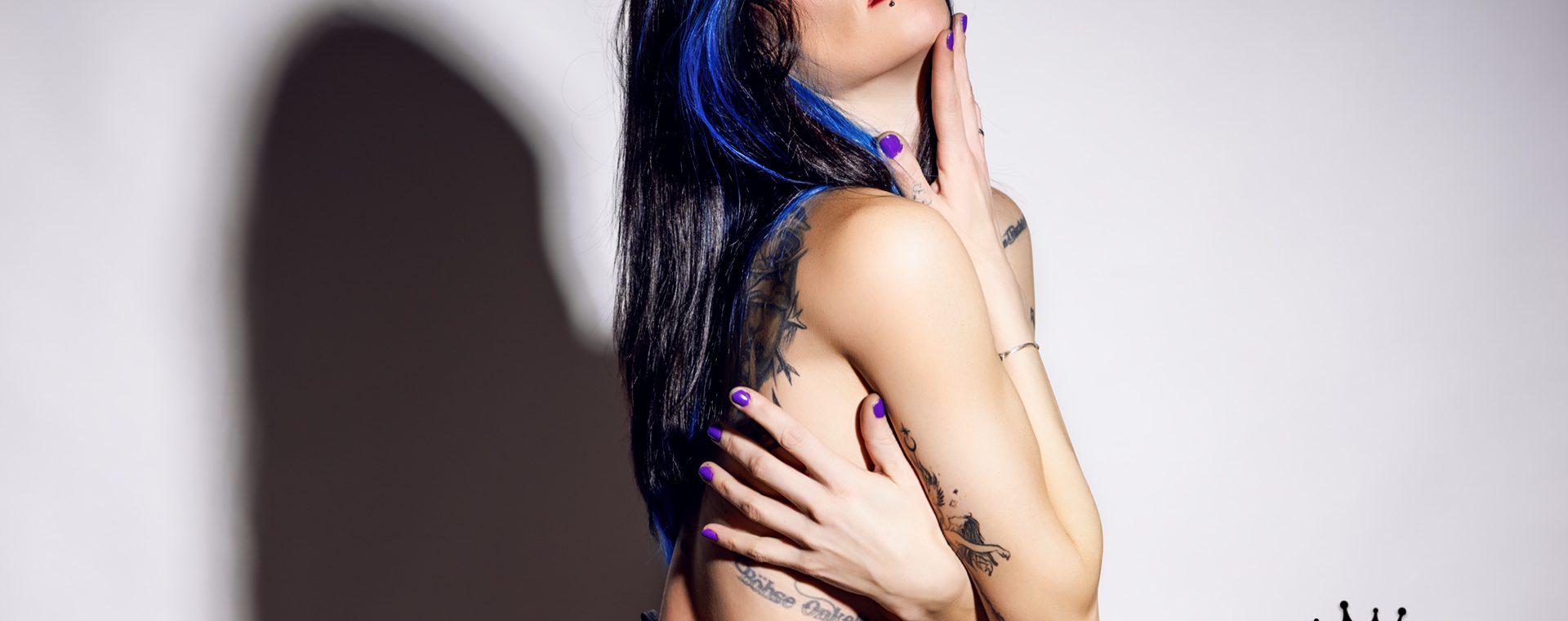 Coco in einer Seitenprofil-Pose, die Arme vor der Brust verschränkt, den Kopf in den Nacken gelegt und die Augen geschlossen. Sie trägt den goldenen Realise Badeanzug tief sitzend an der Hüfte.