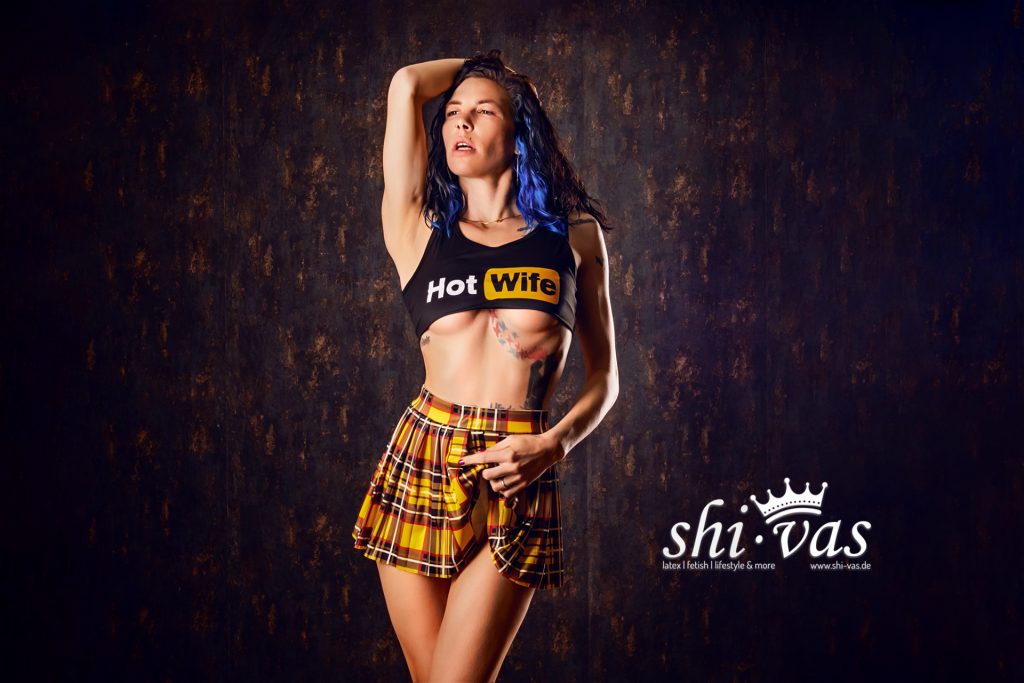 Coco hebt einen Arm über den Kopf, trägt Crop-Top und Minirock, der Körper ist gestreckt und leicht zur Seite gedreht