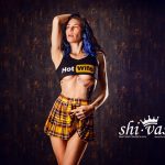 Coco hebt einen Arm über den Kopf, trägt Crop-Top und Minirock, der Körper ist gestreckt und leicht zur Seite gedreht