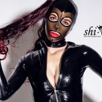 Close-Up von Coco mit Feitico-Latexmaske, rotem Lippenstift und leicht geöffnetem Reißverschluss.