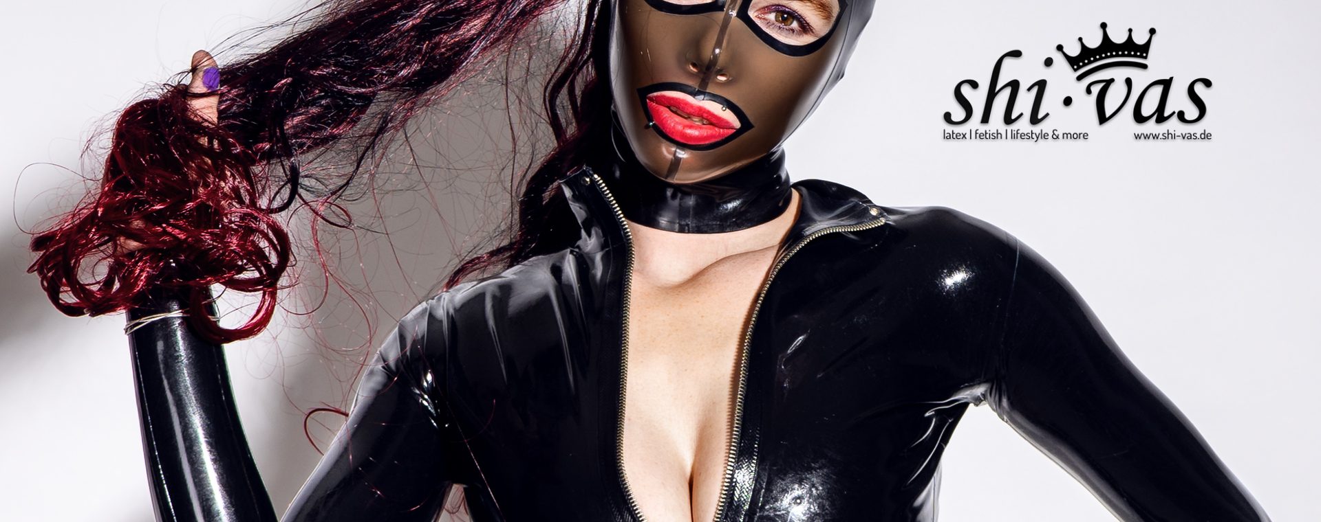 Close-Up von Coco mit Feitico-Latexmaske, rotem Lippenstift und leicht geöffnetem Reißverschluss.
